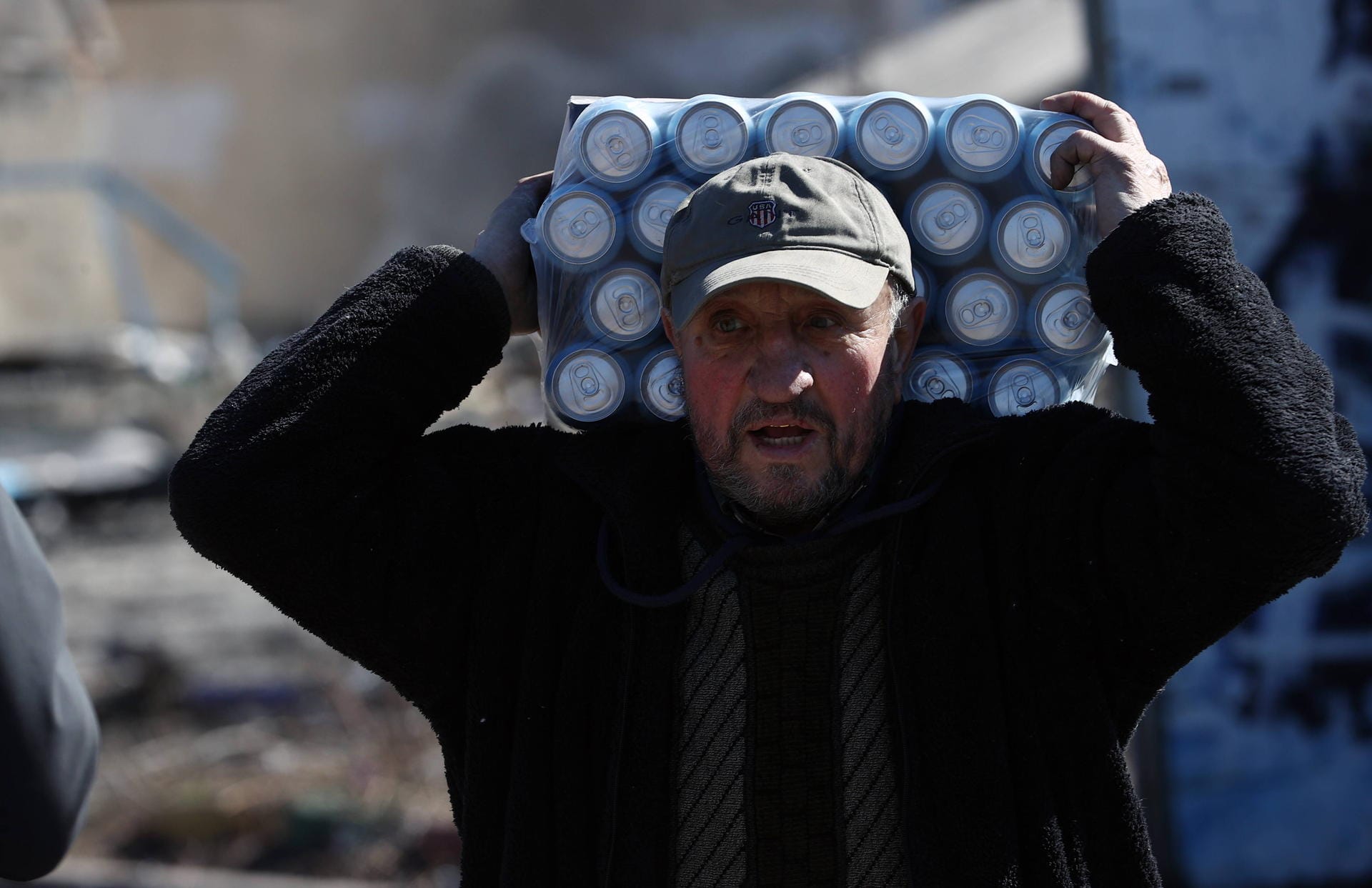 Ein Mann trägt Getränke auf dem Rücken: Mehr als 100.000 Menschen sollen immer noch in der unter Beschuss stehenden Stadt ausharren.