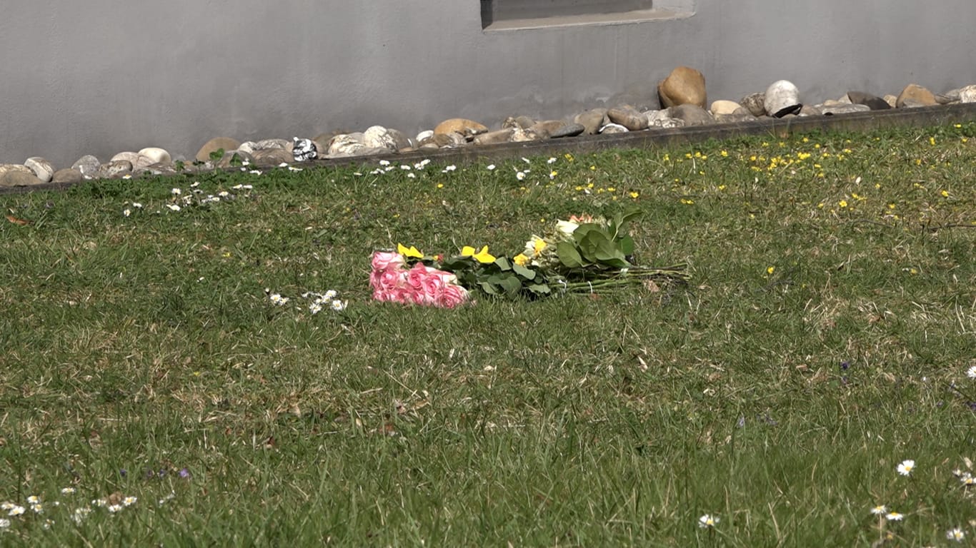 Blumen liegen vor dem Gebäude, aus dem ein Mädchen vom Balkon im fünften Stock stürzte und tödliche Verletzungen erlitt.