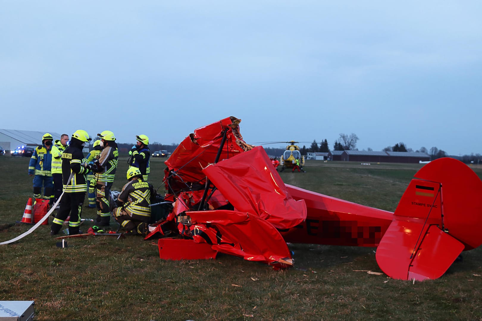 Feuerwehrleute sind am Absturzort eines Sportflugzeugs im Einsatz. Ein Pilot ist in einem Doppeldecker im bayerischen Günzburg abgestürzt und schwer verletzt worden