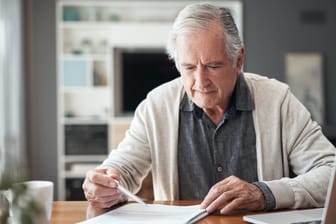 Älterer Mann sichtet Unterlagen (Symbolbild): Bei der Rente gibt es noch immer Unterschiede zwischen Ost und West.