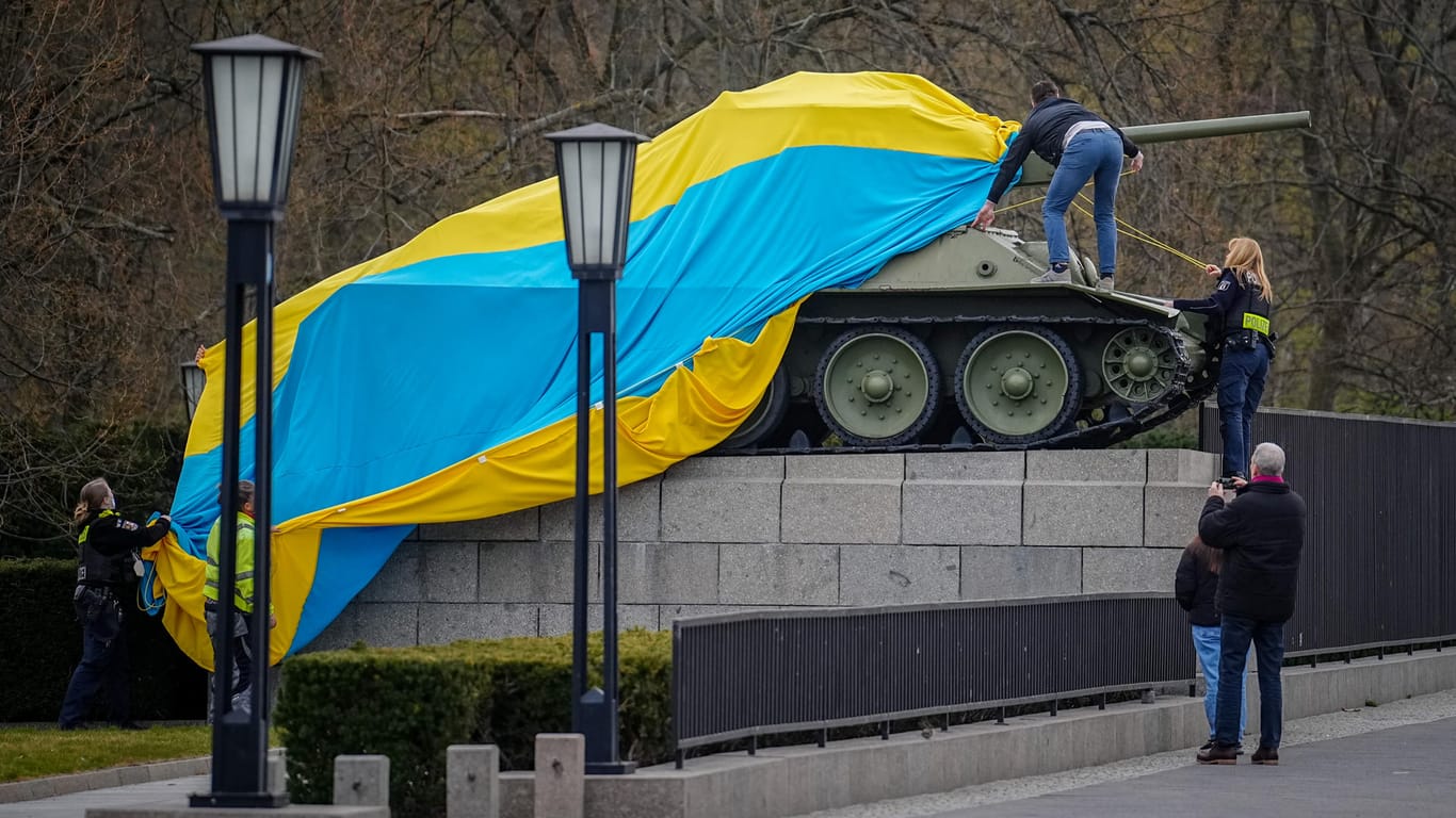 Polizeibeamte entfernen die Flagge der Ukraine von einem historischen Panzer am Sowjetischen Ehrenmal an der Straße des 17. Juni: Kurzzeitig war der Panzer in die ukrainische Flagge gehüllt