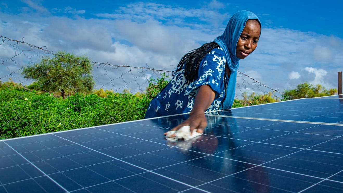 Eine Frau säubert die Sonnenkollektoren ihrer Nachbarschaft in Mauretanien: Kleine Anlagen tragen ebenso zum globalen grünen Stromrekord bei wie riesige Wind- und Solarparks.