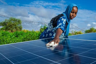 Eine Frau säubert die Sonnenkollektoren ihrer Nachbarschaft in Mauretanien: Kleine Anlagen tragen ebenso zum globalen grünen Stromrekord bei wie riesige Wind- und Solarparks.