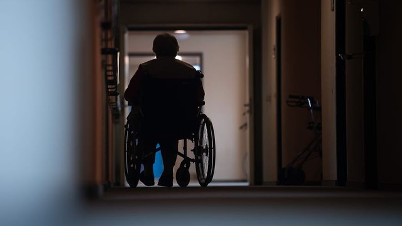 Eine Frau sitzt in einem Heim in einem Rollstuhl auf einem Gang