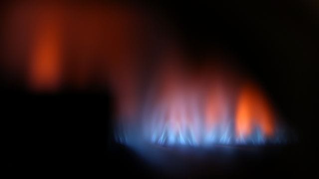 Eine Gasflamme brennt hinter dem Sichtfenster eines Gas-Durchlauferhitzers. Eine Gasflamme brennt hinter dem Sichtfenster eines Gas-Durchlauferhitzers.