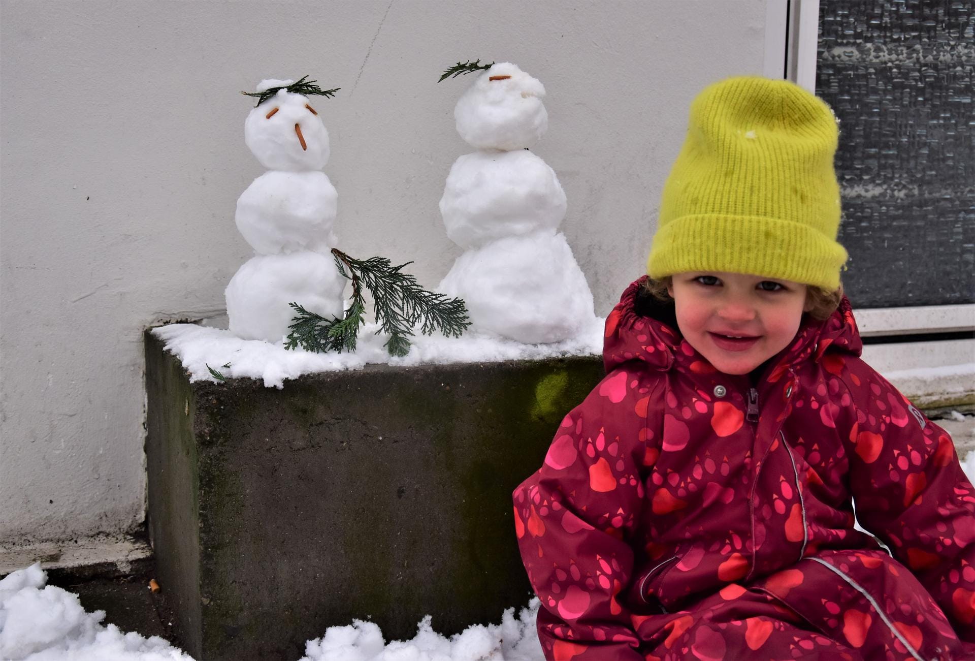 Ein Kind sitzt neben ihren Schneemännern: Marie (4) aus Ottensen hatte Freude am Neuschnee in Hamburg.