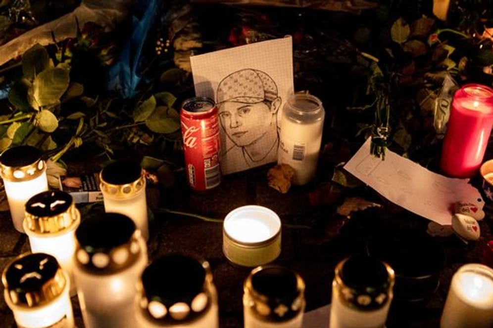 Ein gezeichnetes Porträt, Blumen und Kerzen liegen an einer provisorischen Gedenkstätte, wo der schwedische Rapper Einar 2021 erschossen wurde.