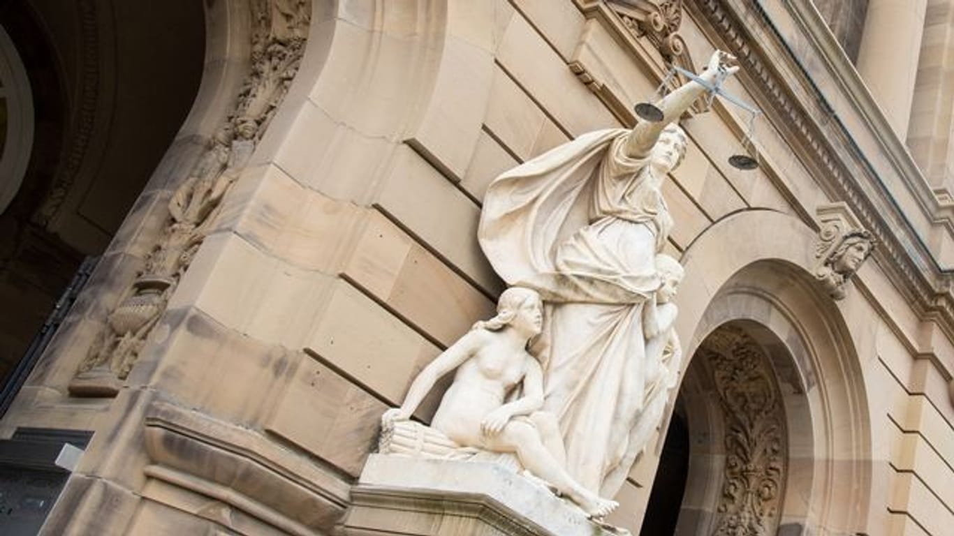 Eine Justitia-Figur steht vor einem Gerichtsgebäude