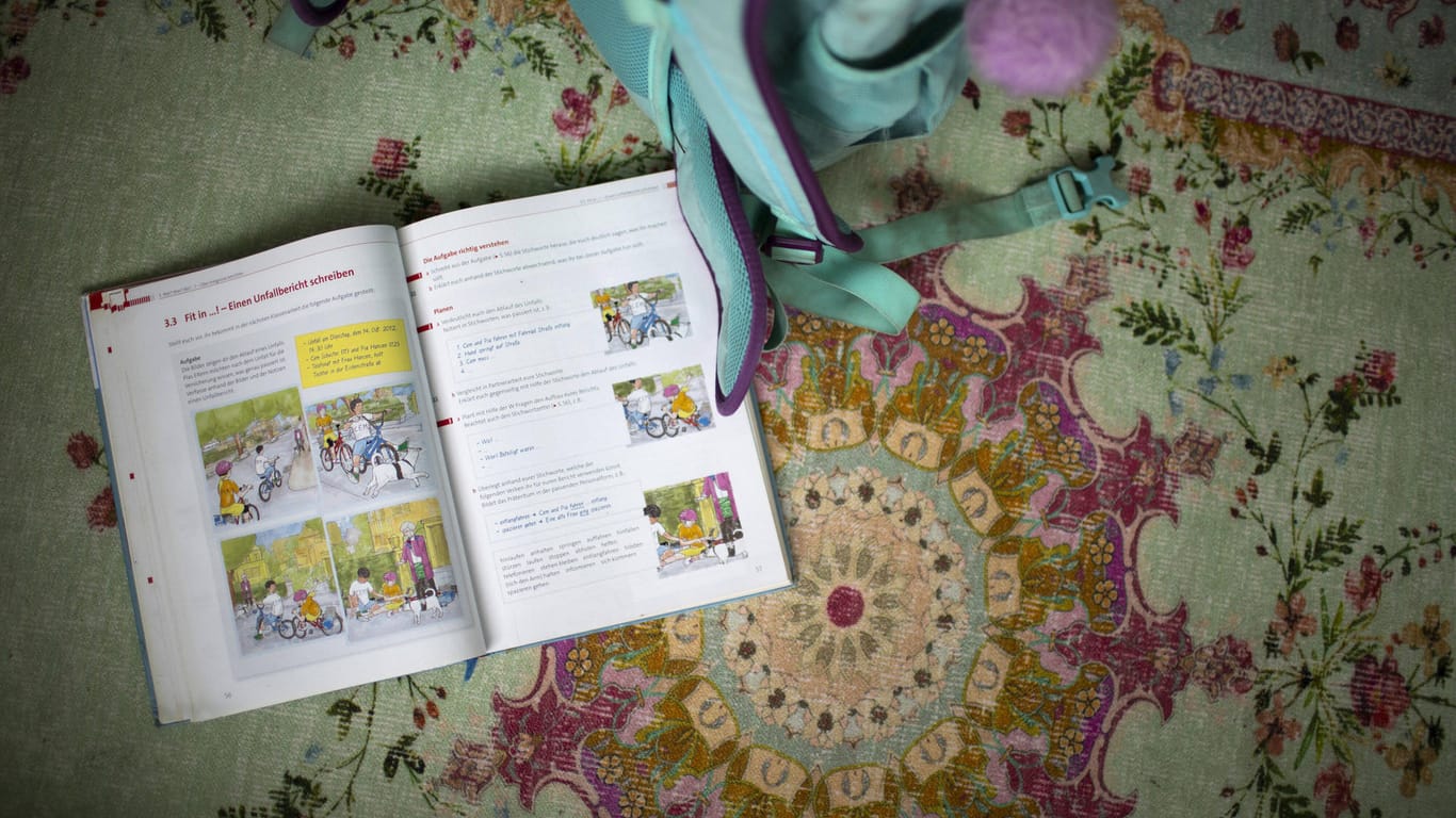 Ein Schulbuch neben einem Schulranzen (Symbolbild): Laut Schulaufsicht sei der Text auf Wunsch der Klasse gelesen worden.