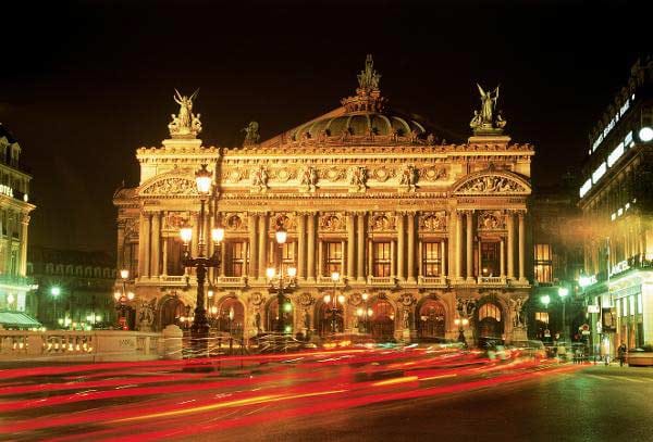 Nachtaufnahme der beleuchteten Oper und Straßenverkehr an der Place de l'Opera in der französischen Hauptstadt Paris.