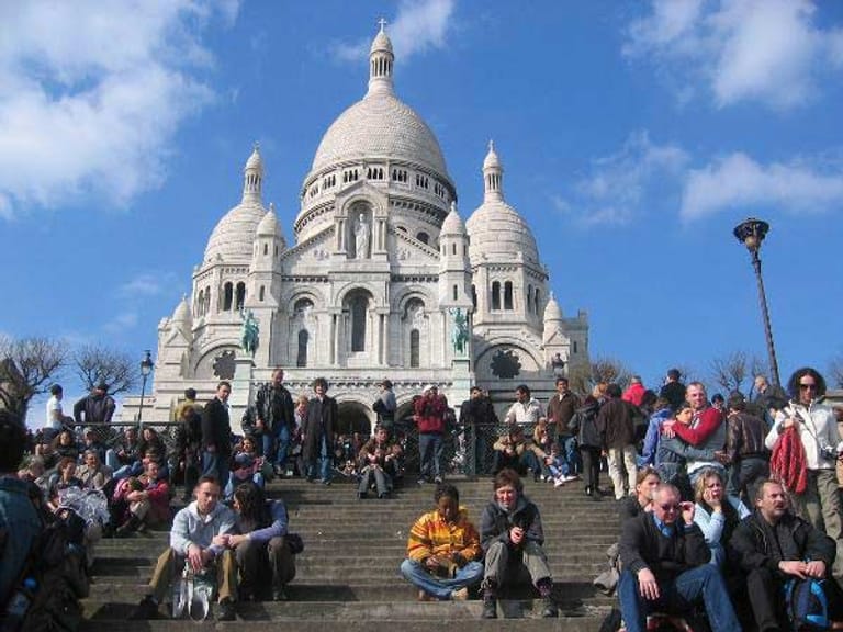 Hunderte Touristen und Besucher sitzen auf der Treppe vor der Kirche Sacre Coeur auf dem Hügel Montmartre in Paris.