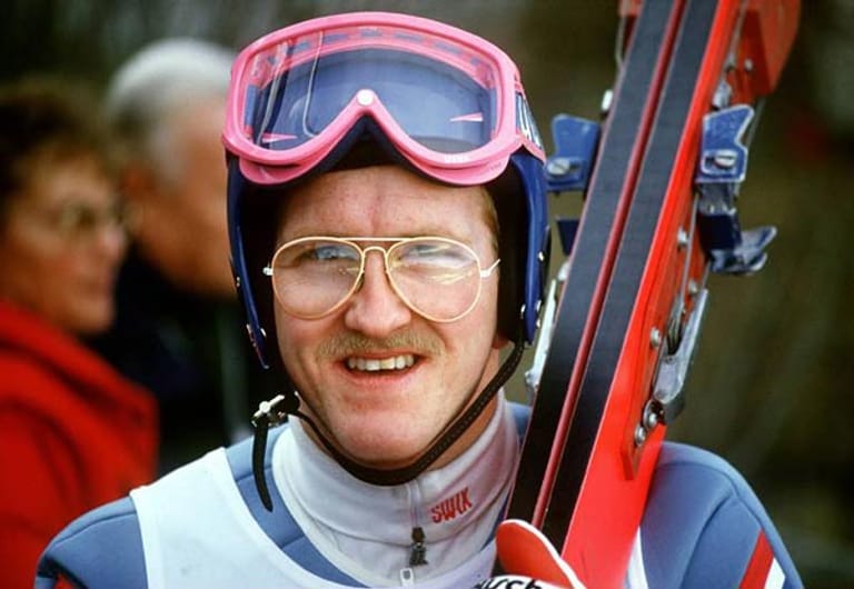 Gestatten: Michael Edwards, besser bekannt als Eddie "The Eagle". Er ist der erste Skispringer, der für Großbritannien bei Olympischen Winterspielen an den Start geht. Edwards ist ein notorischer Hinterherflieger, was seiner Popularität allerdings nicht schadet. Aufgrund dieser Tatsache ändert das IOC 1990 die Regeln, so dass er die Qualifikation für die nachfolgenden Olympischen Spiele nicht mehr schafft.