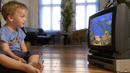 Kleiner Junge sitzt gespannt vor dem Fernseher.