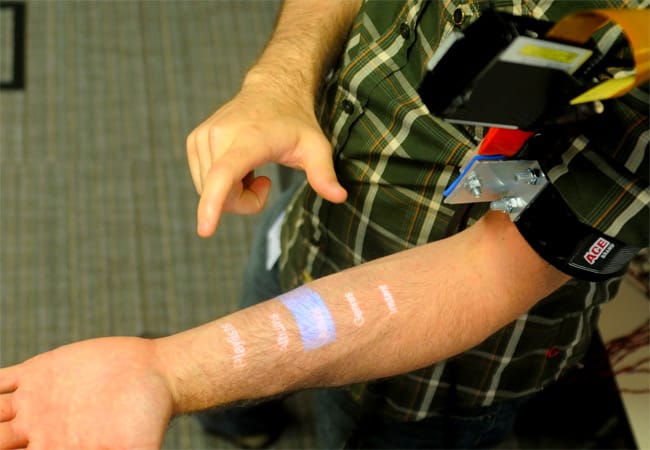 Ein winziger, in dem Armband integrierter "Pico"-Projektor bildet die Menüführung des Handys auf dem Unterarm ab.