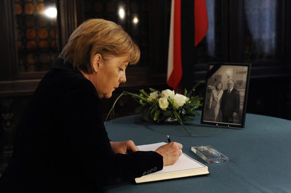 Angela Merkel trägt sich in ein Kondolenzbuch in der polnischen Botschaft in Berlin ein.