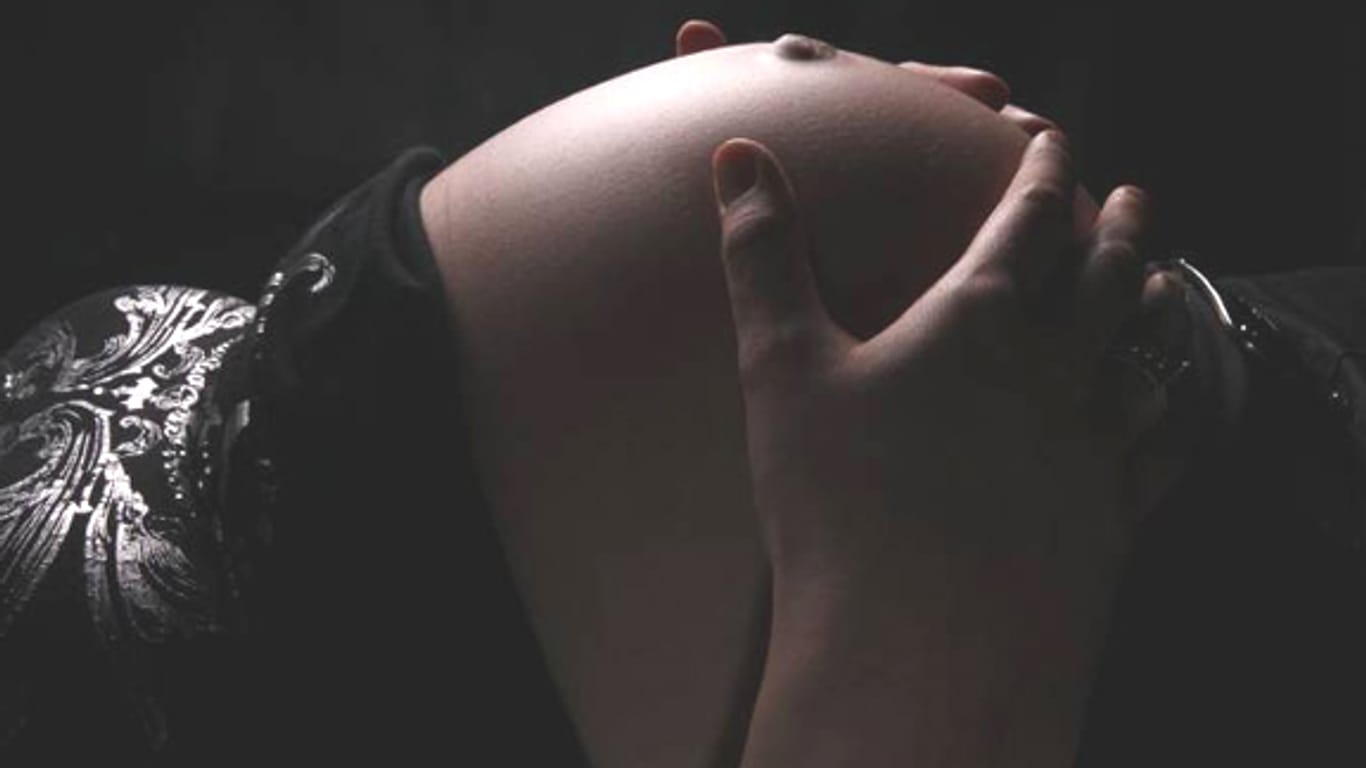 Schwangere hält die Hände an ihren Bauch.