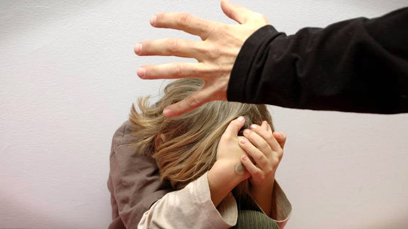 Ein Mann erhebt seine Hand bedrohlich gegen ein ängstliches Kind.