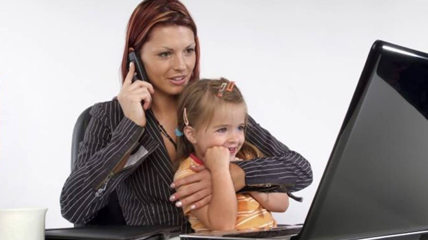 Junge Frau arbeitet am Computer, mit Kind auf dem Schoß.