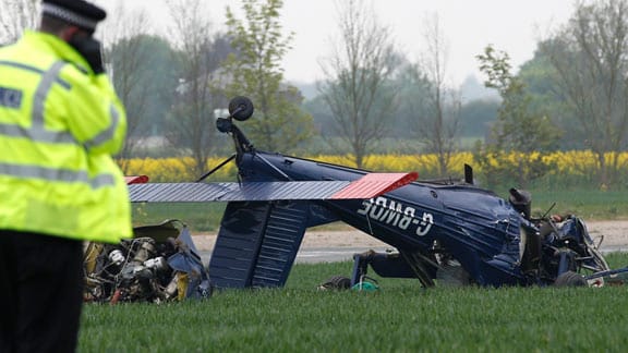 Ein Polizeibeamter betrachtet die stark beschädigte Unfallmaschine auf dem Hinton-in-the-Hedges Airfield in der englischen Grafschaft Northamptonshire Ein Polizeibeamter betrachtet die stark beschädigte Unfallmaschine auf dem Hinton-in-the-Hedges Airfield in der englischen Grafschaft Northamptonshire