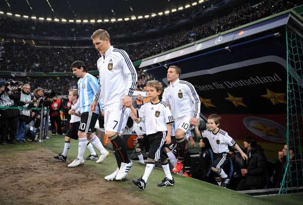 Bastian Schweinsteiger, Lukas Podolski und Lionel Messi laufen mit Fußballkindern in das Stadion ein.
