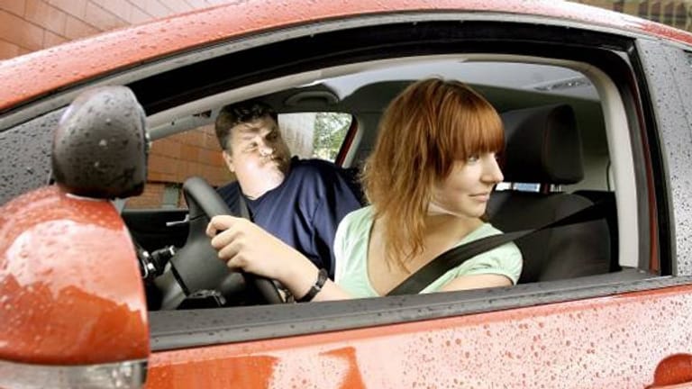 Junges Mädchen im Auto am Steuer, daneben der Fahrlehrer.