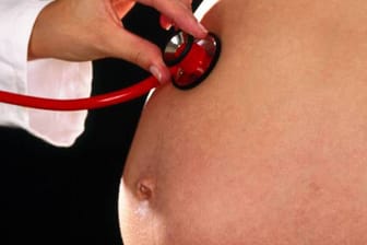 Arzt hört mit Stethoskop Schwangere ab.