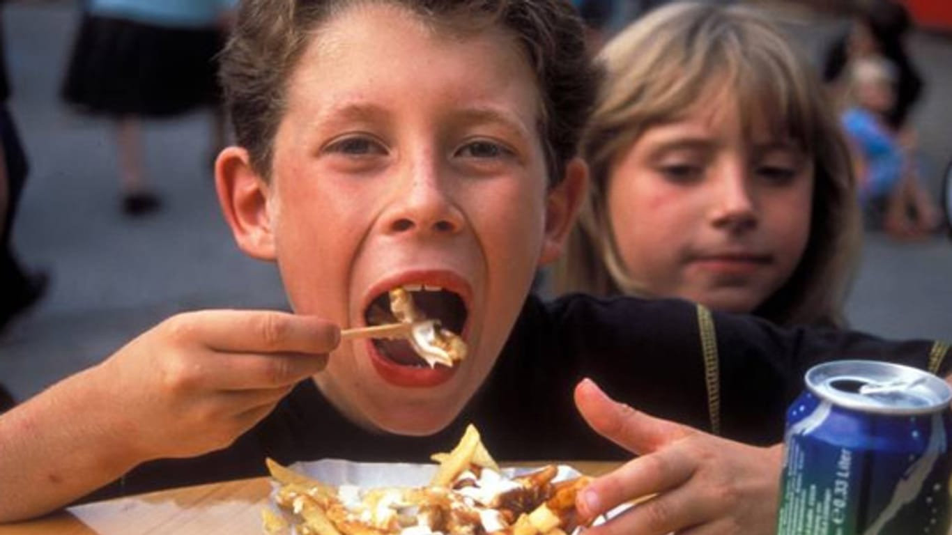 Ein Junge isst eine Portion Pommes mit Soße.