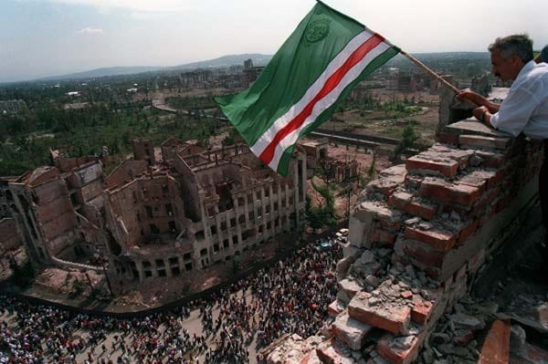 Vom Dach des zerstörten Präsidentenpalastes schwenkt ein Tschetschene die Fahne der Kaukasus-Republik