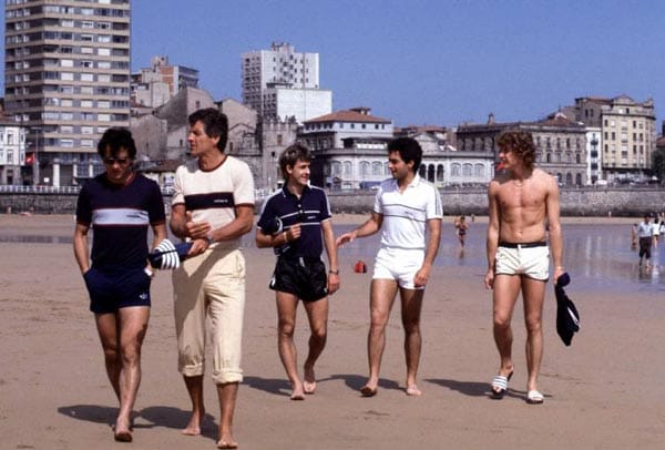 Felix Magath, Pierre Littbarski, Hansi Müller und Toni Schumacher (v.li.) wagen einen Strandspaziergang in ganz kurzen Hosen. Nur Co-Trainer Erich Ribbeck fällt aus der Rolle.