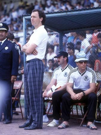 Ein Rapper und seine Bodyguards? Nein, Franz Beckenbauer im karierten Beinkleid, dahinter Horst Köppel und Berti Vogts (re.) als Adiletten-Duo.