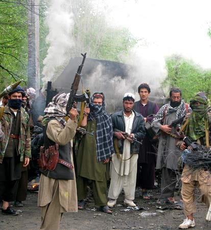 Nach einem Anschlag auf einen deutschen Konvoi posieren Taliban-Kämpfer vor dem Wrack.