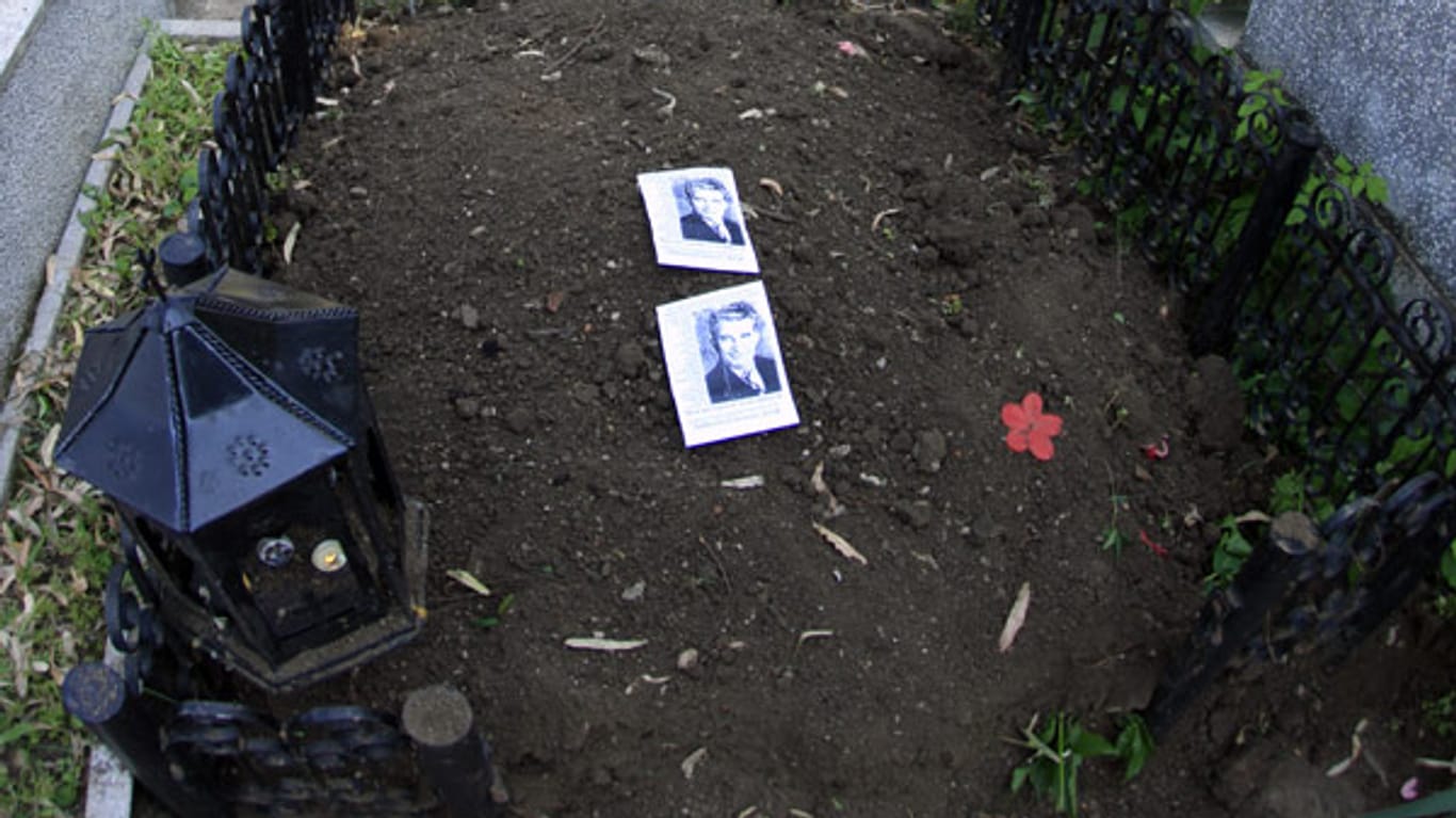 Bilder Ceausescus liegen auf dem frisch wieder zugeschütteten Grab, nachdem DNA-Proben entnommen wurden