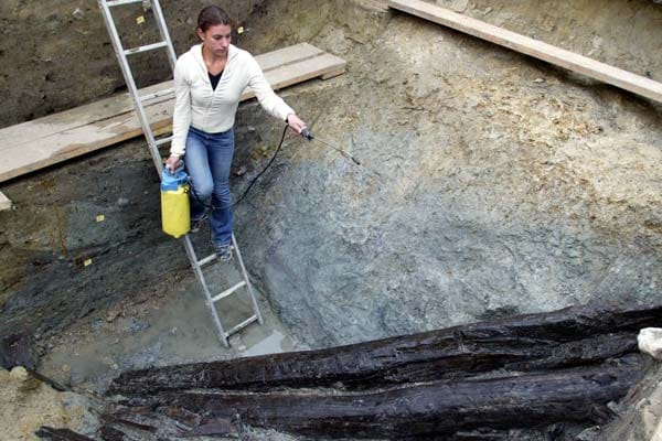 Archäologie: In den vergangenen Jahrzehnten machten Forscher immer wieder Entdeckungen auf der Heuneburg. Hier besprüht eine Archäologin im Jahr 2004 Bauhölzer aus der frühen Eisenzeit, damit diese nicht austrocknen. Sie wurden im sieben Meter tiefen Burggraben entdeckt.