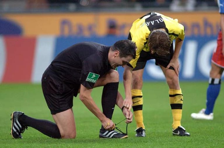 Ebi Smolarek von Borussia Dortmund hilft Schiedsrichter Knut Kircher beim Schuhe binden.