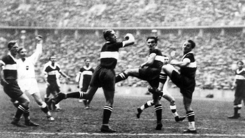 Handball auf dem Feld - die Älteren werden sich erinnern. 1936 in Berlin ist Feldhandball sogar olympisch. 100.000 Zuschauer sind dabei, als Deutschland gegen Österreich (Spielszene) 10:6 gewinnt und Gold holt. 1938 holen die Deutschen auf dem Feld und in der erstmals in der Halle ausgetragenen WM den Titel.