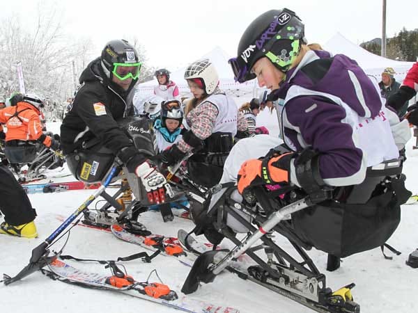 Martin Braxenthaler (l.) vermittelt den Schülern auf was sie beim Monoskifahren achten müssen und wie mit den Skistöcken mit Kufen umgegangen wird.