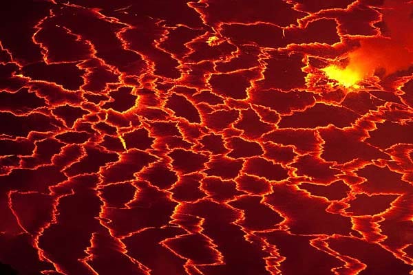 Nahansicht: Im Vulkankessel wogt die Lava, fauchend legt sich ihre silbrig-schwarze Kruste in Falten. Aus Rissen lodert zischend die Glut hervor.