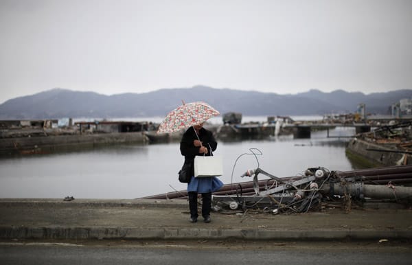 Eine Frau steht an einer Straße zwischen den Überresten der Stadt Ishinomaki.