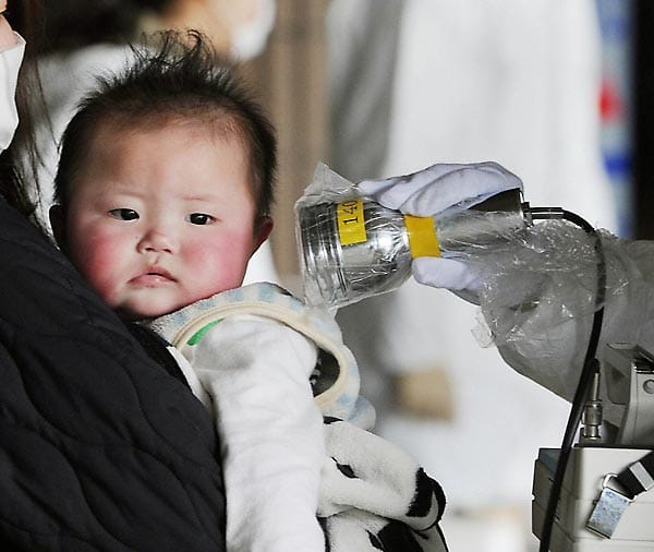 Ein Strahlenkontrolleur misst bei einem Baby in Fukushima Stadt die radioaktive Belastung am 24. März 2011. Nachdem in der Hauptstadt Tokio erhöhte Werte von radioaktivem Jod und Cäsium im Trinkwasser nachgewiesen wurden, sollen Babys dort kein Leitungswasser mehr trinken.