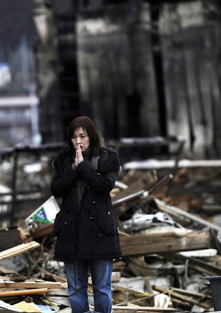 Eine Frau hat eine Leiche in der vom Tsunami betroffenen Stadt Kesennuma gefunden und presst ihre Handflächen zusammen. Auch am 25. März 2011 werden noch immer rund 13.000 Menschen in Japan vermisst.