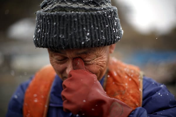 Ein Fischer bricht in Tränen aus, nachdem er die Trümmer seines zerstörten Bootes in Yamada gefunden hat.
