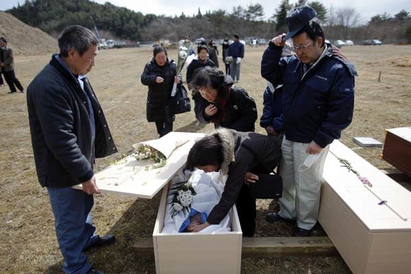 Angehörige der Opfer des Erdbebens und Tsunamis nehmen in Kesennuma bei einer Trauerfeier mit anschließender Massenbeisetzung am offenen Sarg Abschied.