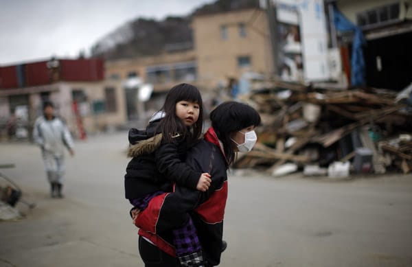 Eine Frau trägt ihre Tochter durch die Trümmer ihrer Heimatstadt Yamada.