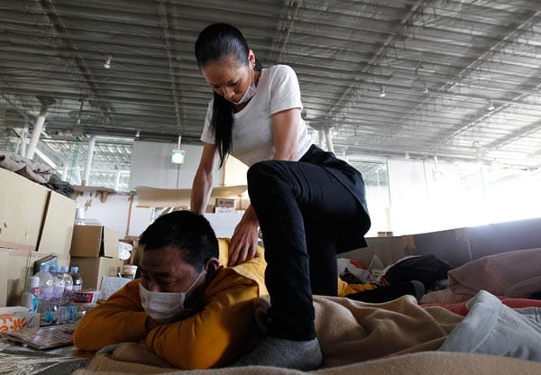 Im Evakuierungslager von Koriayama, 70 Kilometer von der Atomanlage Fukushima entfernt, wird ein Mann von einer Helferin massiert.