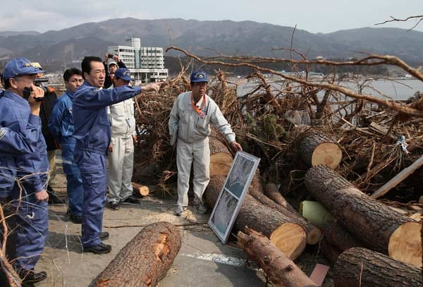 Japans Premierminister Naoto Kan besucht in blauer Arbeitskleidung den Ort Rikuzentakata.