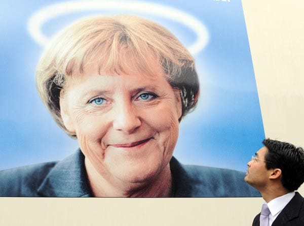 Rösler schaut auf ein Merkel-Bild mit Heiligenschein. Seit Mai 2011 ist er Vizekanzler und Wirtschaftsminister in ihrem Kabinett und zudem neuer Parteichef der Liberalen.
