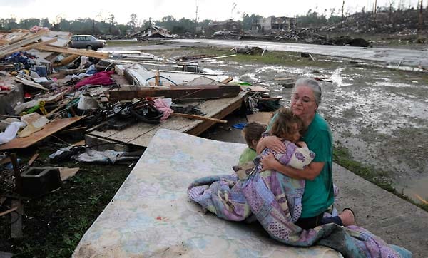 Eine Frau sitzt mit ihren Enkelkindern auf einer Matratze. Vor dem Tornado befand sich dort der Garten. Das Zuhause der Familie ist völlig zerstört worden. Eine Frau sitzt mit ihren Enkelkindern auf einer Matratze. Vor dem Tornado befand sich dort der Garten. Das Zuhause der Familie ist völlig zerstört worden.