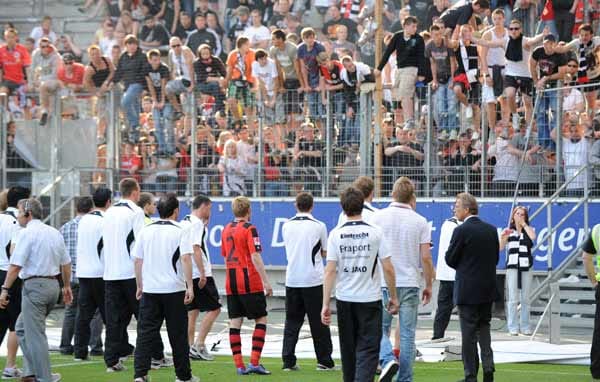 Erst als die Polizei die Lage beruhigt hat, kommen die Frankfurter Spieler wieder zurück, um sich der Kritik der Fans zu stellen.