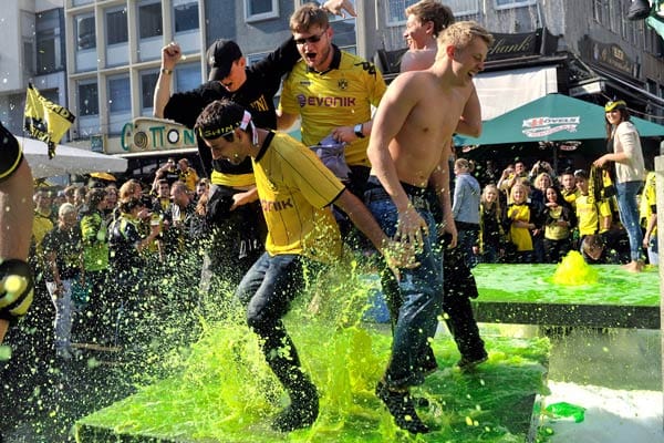 In Dortmund feiern Dortmunder Fans in einem extra gelb eingefärbten Brunnen.