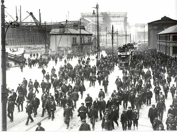 Ein historisches Schwarz-Weiß-Foto zeigt die Queens Road im Belfaster Hafenviertel während die "Titanic" (im Hintergrund) gebaut wird. Ein historisches Schwarz-Weiß-Foto zeigt die Queens Road im Belfaster Hafenviertel während die "Titanic" (im Hintergrund) gebaut wird.